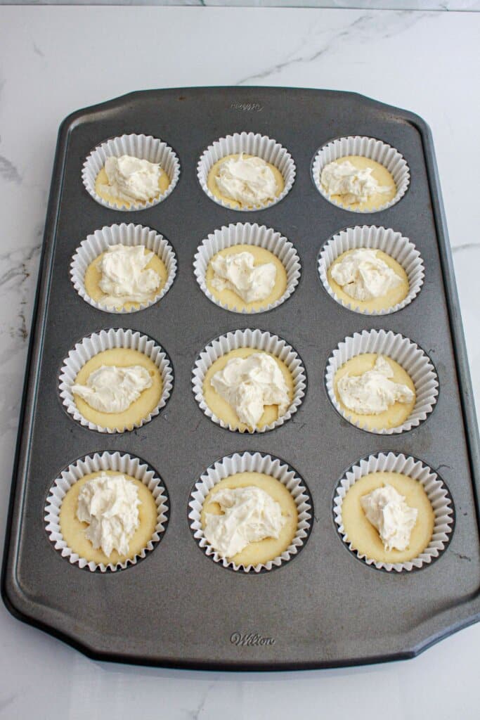 cream cheese filing being added to a muffin pan.