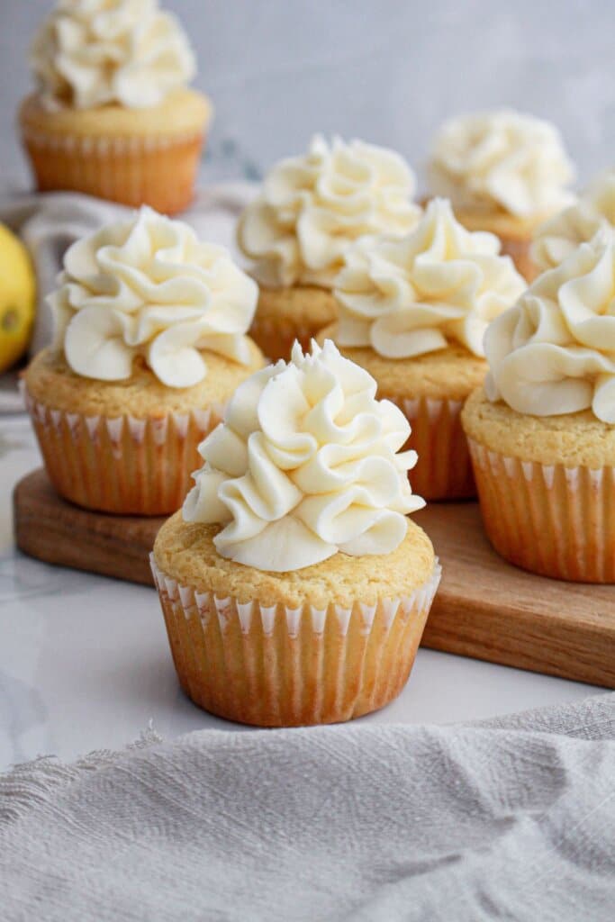 lemon cream cheese cupcakes on a wooden cutting board.