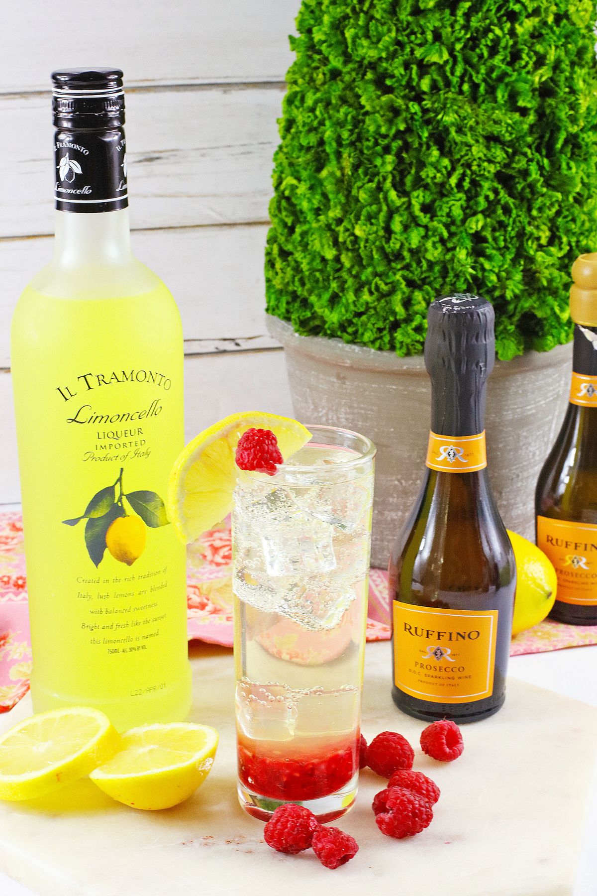 glass of limonello prosecco on a wooden cutting board topped with a slice of lemon.