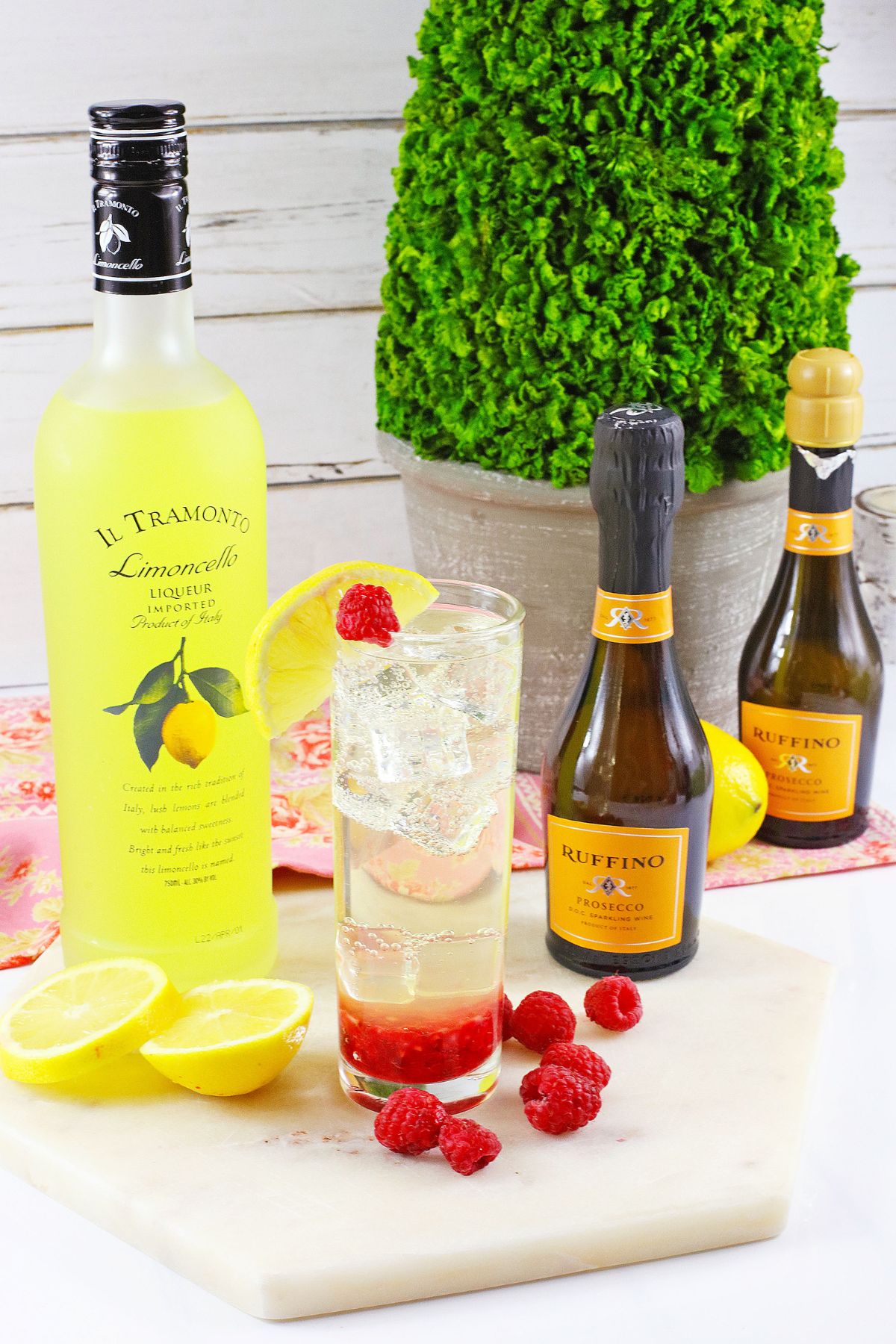 glass of limonello prosecco on a wooden cutting board topped with a slice of lemon.