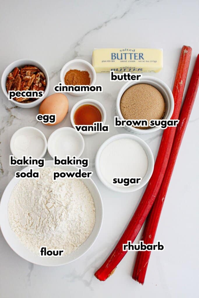 bowls of pecans, cinnamon, egg, butter, baking soda, baking powder, sugar, flour, brown sugar, and rhubarb on a counter.