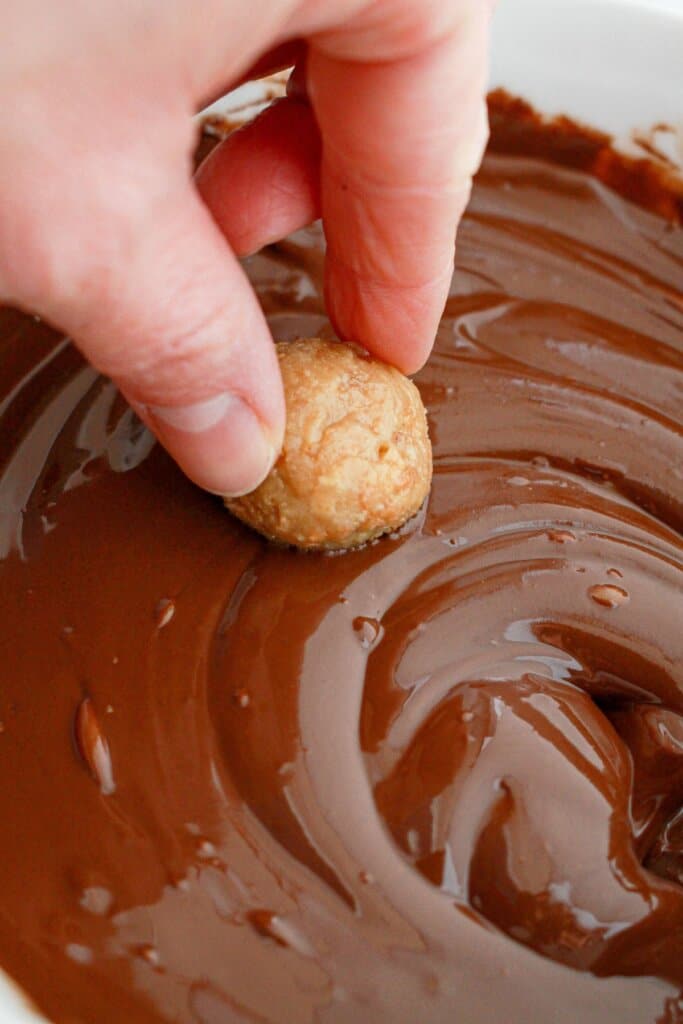 trufle being dipped into melted chocolate.