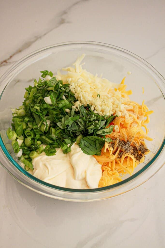 green onions, mayo, mozzarella cheese, cheddar cheese, and basil in a glass bowl.