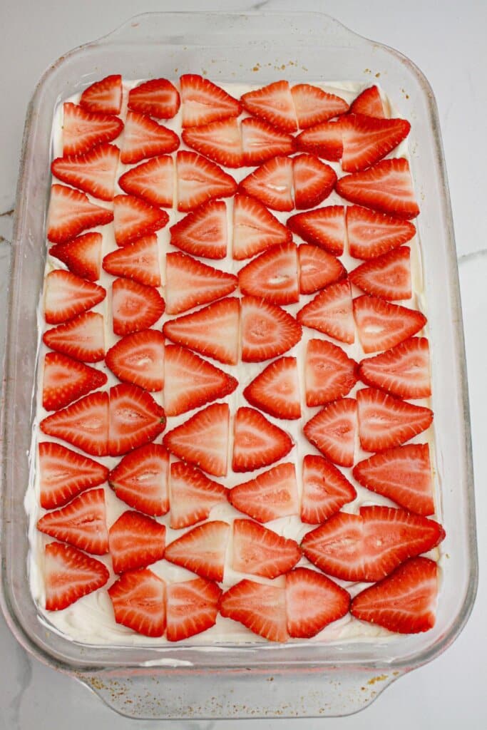 slices of strawberries being layed in a flat layer on a baking dish.