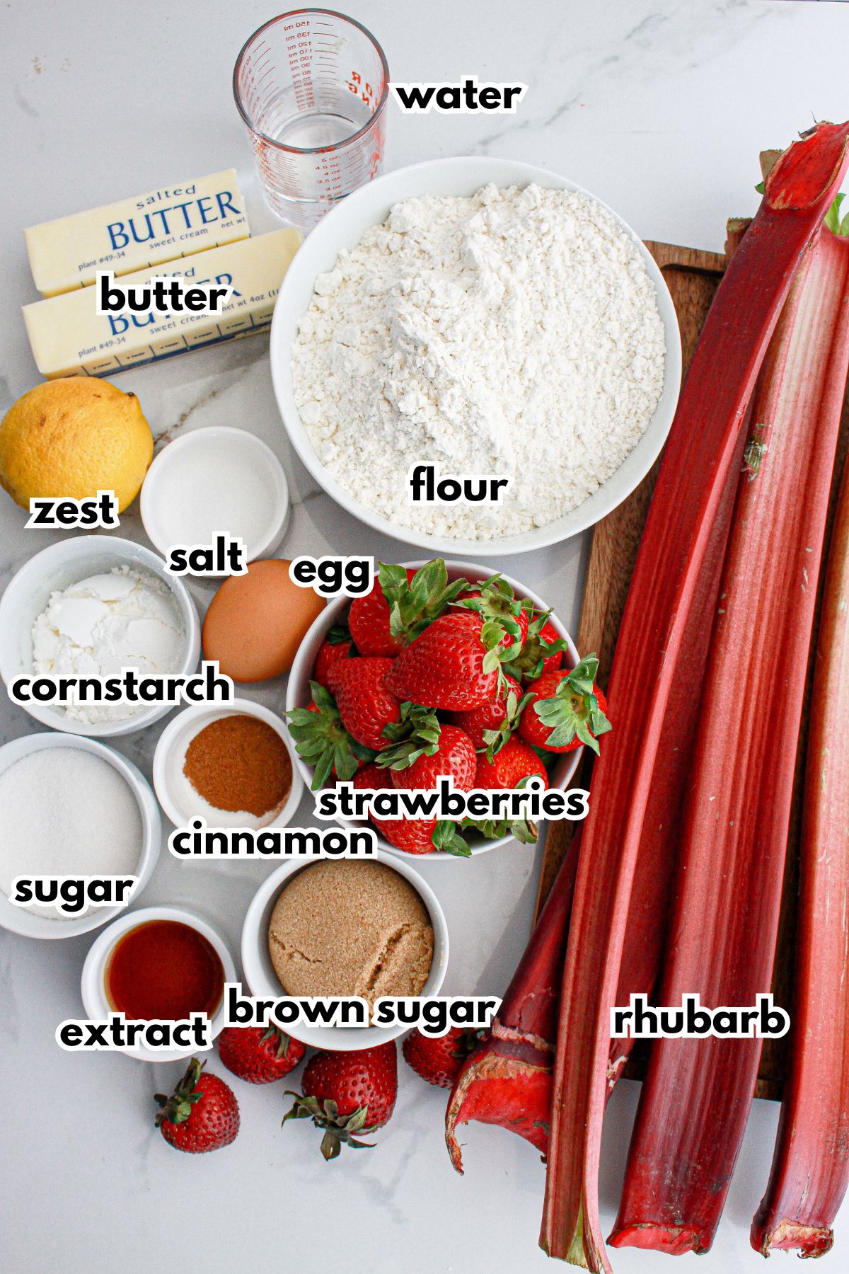 rhubarb, strawvberries, butter, water, lemon, salt, cornstarch, sugar, cinnamon, vanilla, and brown sugar on a counter.