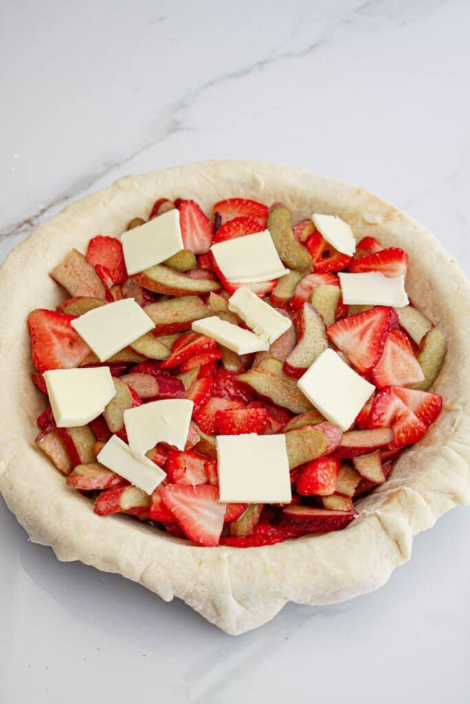 pie filling and pats of butter being to the baking dish.