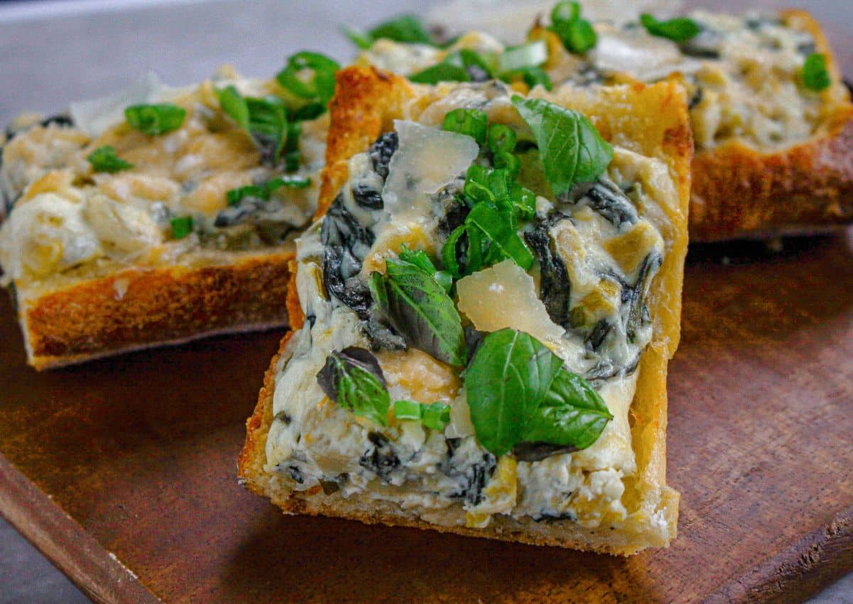 two slices of spinach artichoke stuffed garlic bread on a plate.