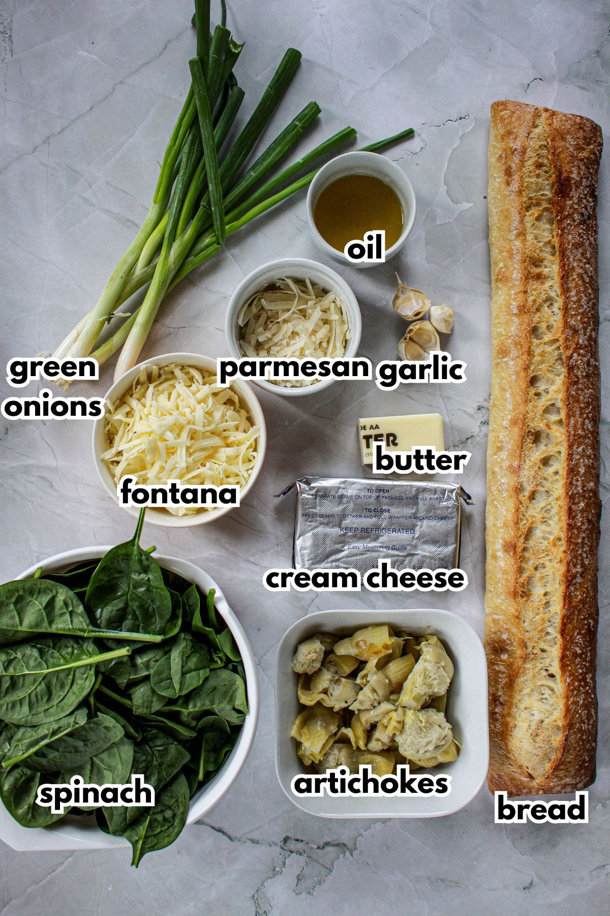 bowls of fontana cheese, parmesan cheese, oil, garlic, butter, spinach, artichokes, bread, cream cheese, and green onions on a counter.