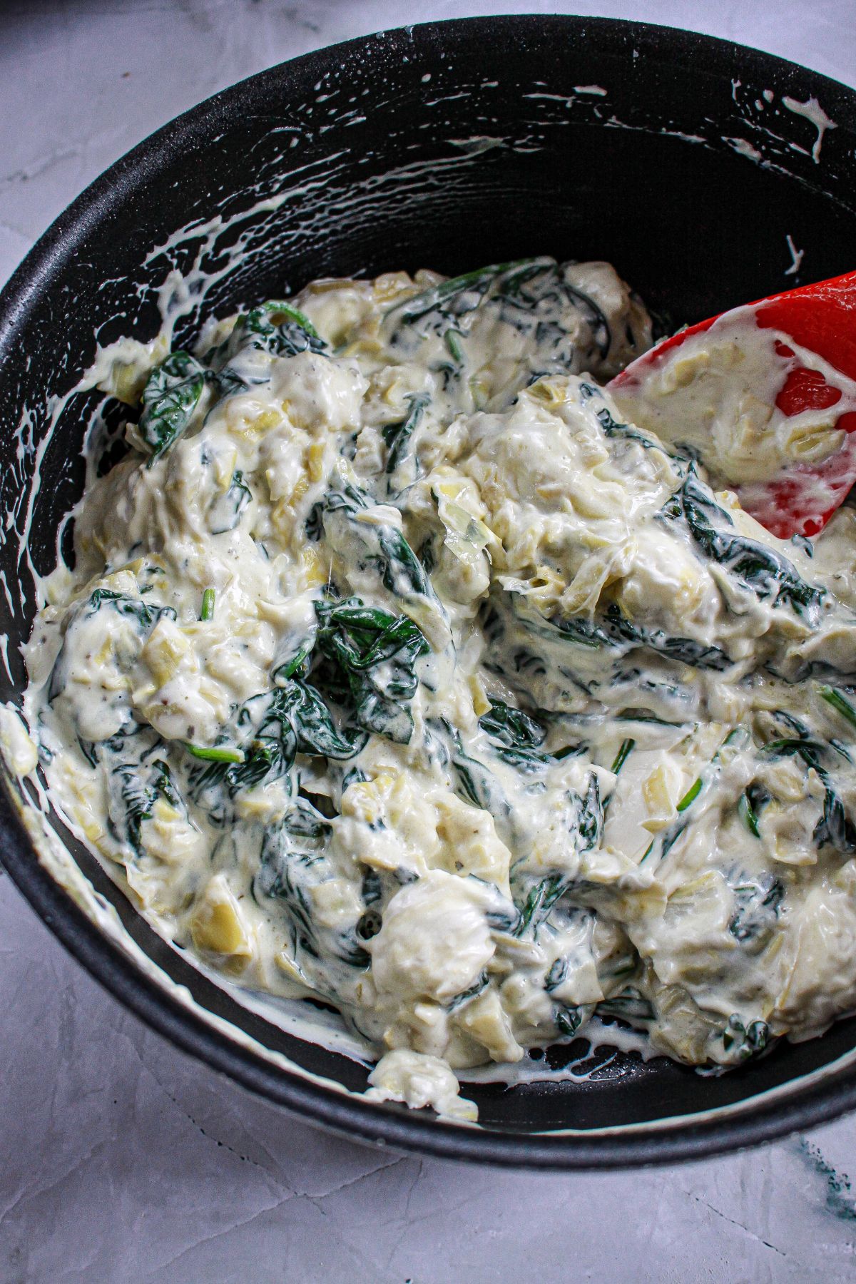 spinach artichoke mixed being cooked in a skillet.