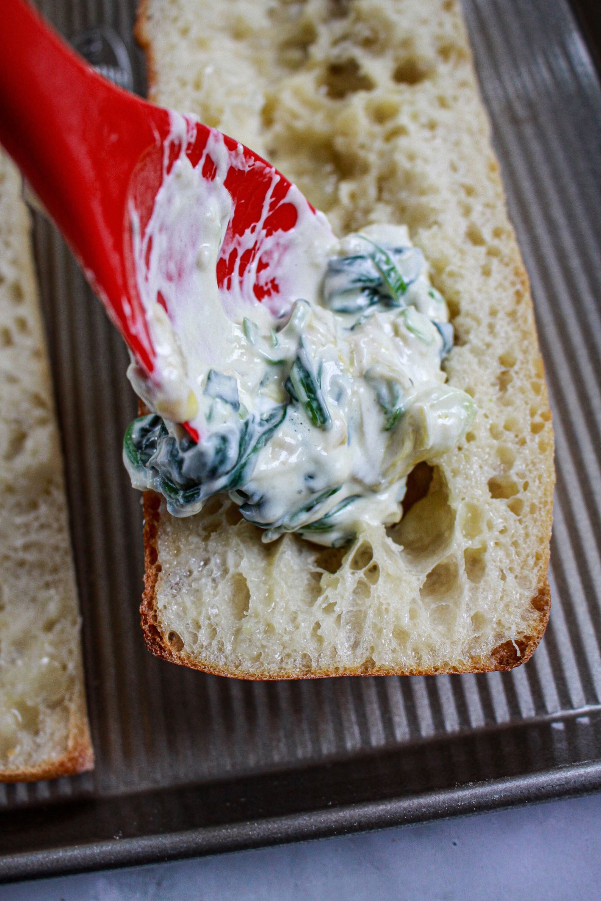 spinach artichoke dip being added to stuffed garlic bread.