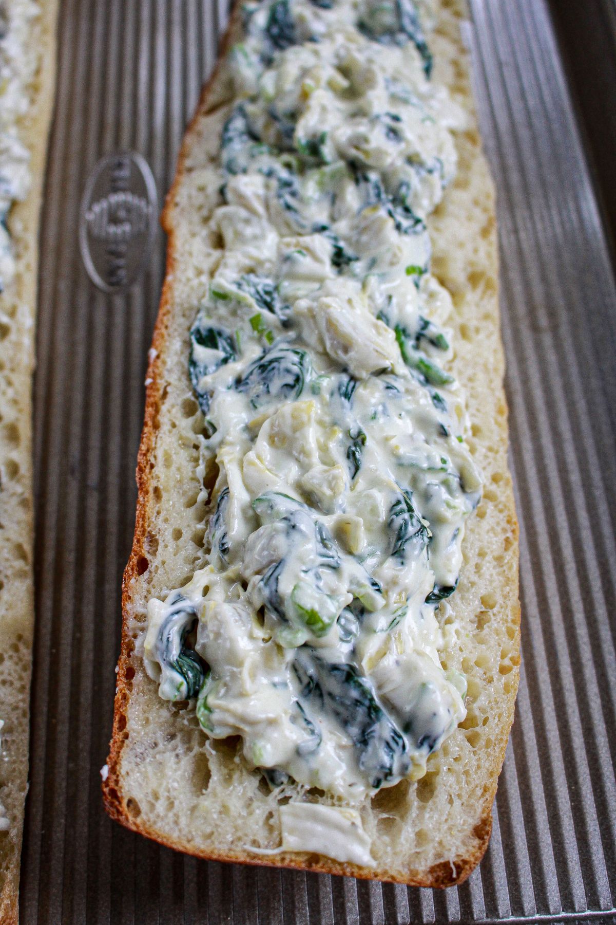 spinach artichoke stuffed garlic bread on a baking sheet.