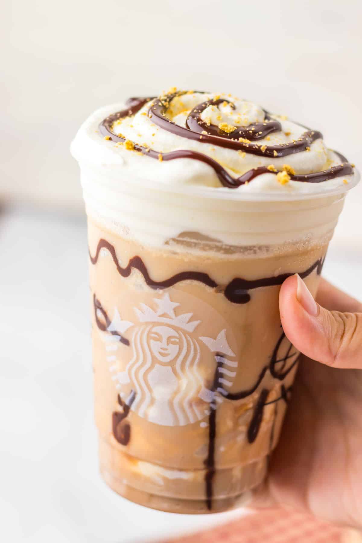 smores frappuccino held in a woman's hand.
