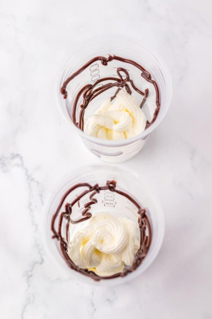 marshmallow cream and hot fudge in cups on a counter.