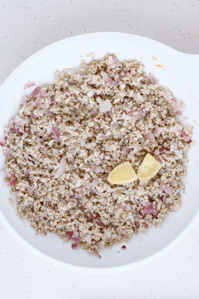 Ground pork, onions, and ginger being cooked in a large skillet.
