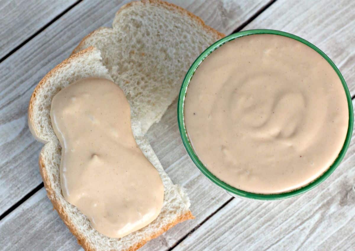 amish peanut butter spread being spread onto a half of a piece of bread.