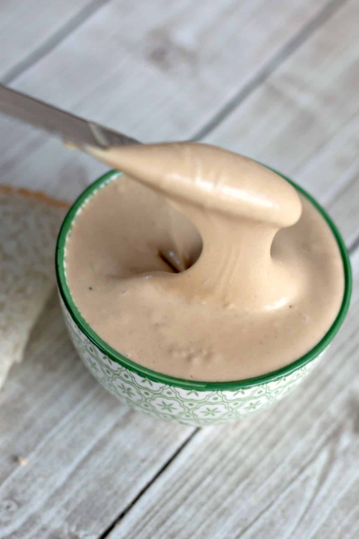 Amish peanut butter spread being removed from a small bowl with a butter knife.