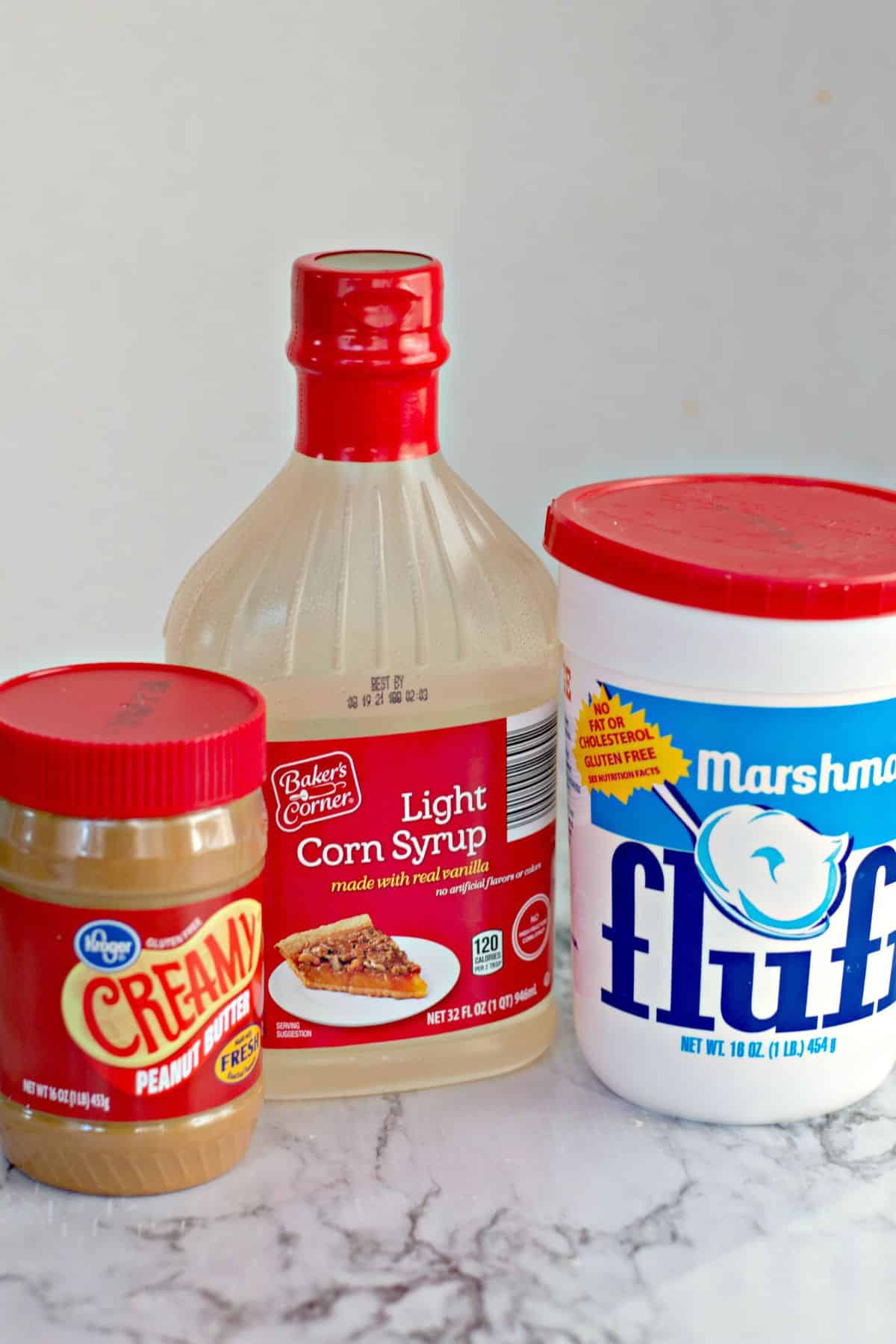 Containers of peanut butter, corn syrup, and marshamllow fluff on a counter.