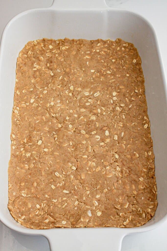 crust being pressed itno a baking dish.