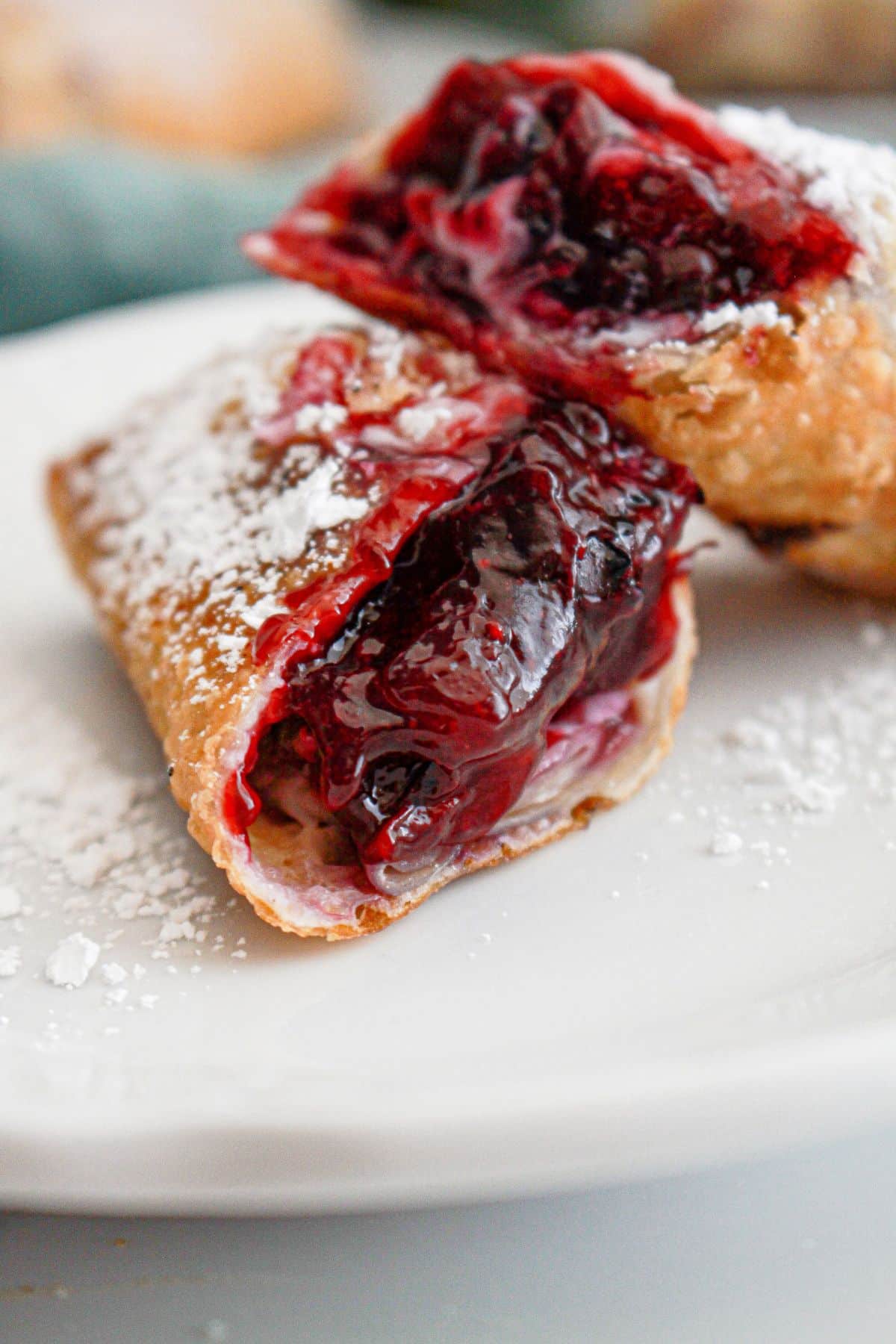 Blueberry cream cheese egg roll on a plate broken in a half.