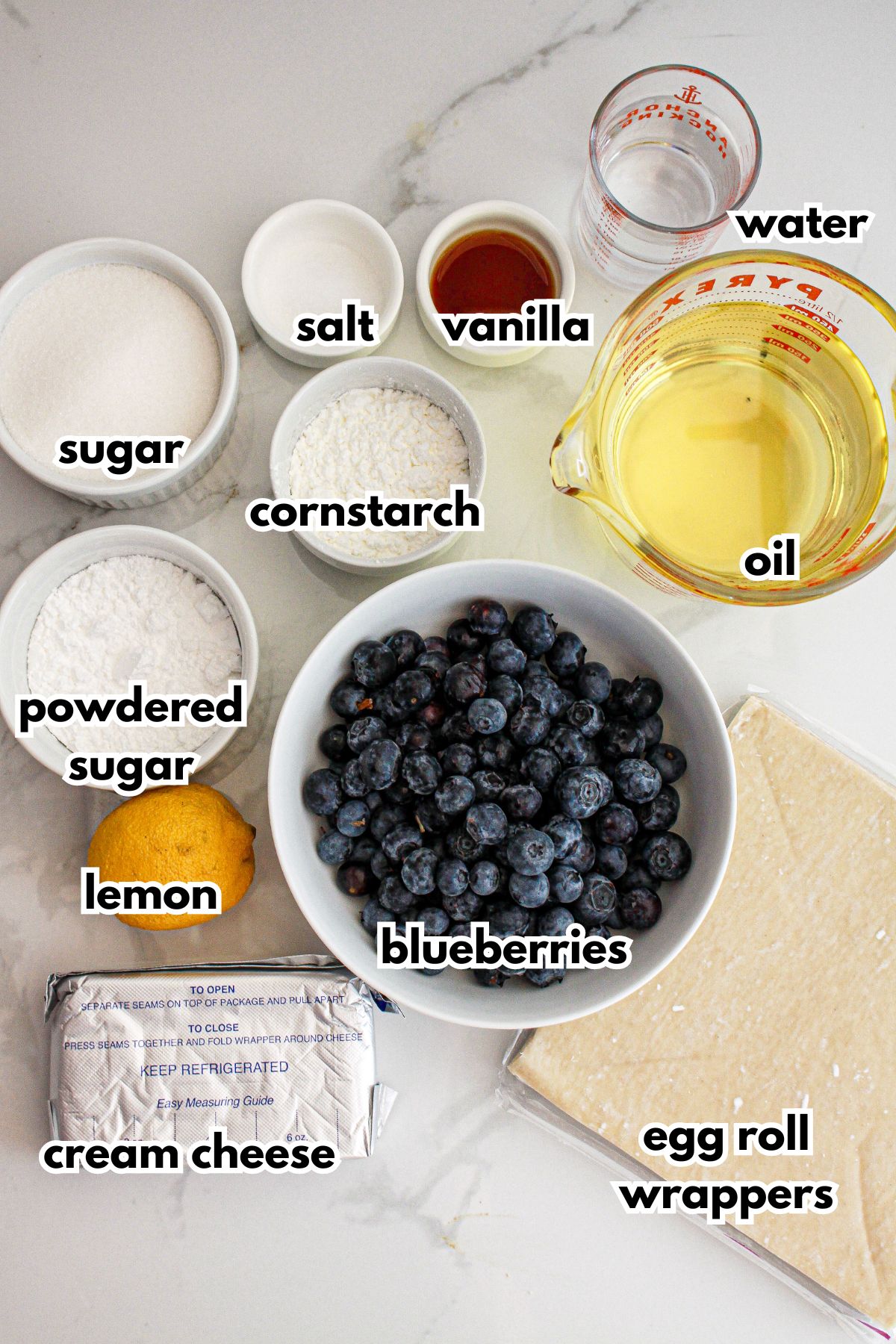 bowls of water, salt, vanilla, sugar, powdered sugar, cornstarch, oil, lemon, blueberries, cream cheese, and egg roll wrappers.