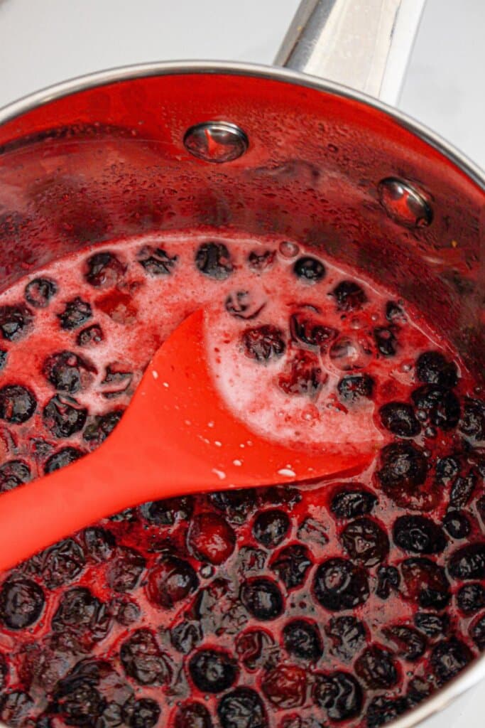 Blueberries being cooke in a saucepan.