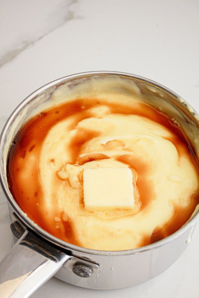 Butter and vanilla being added to custard in a saucepan.
