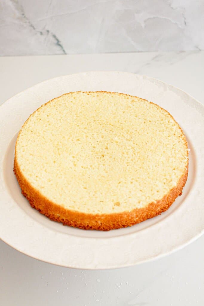 Round cake layer cut in half on a cake plate.