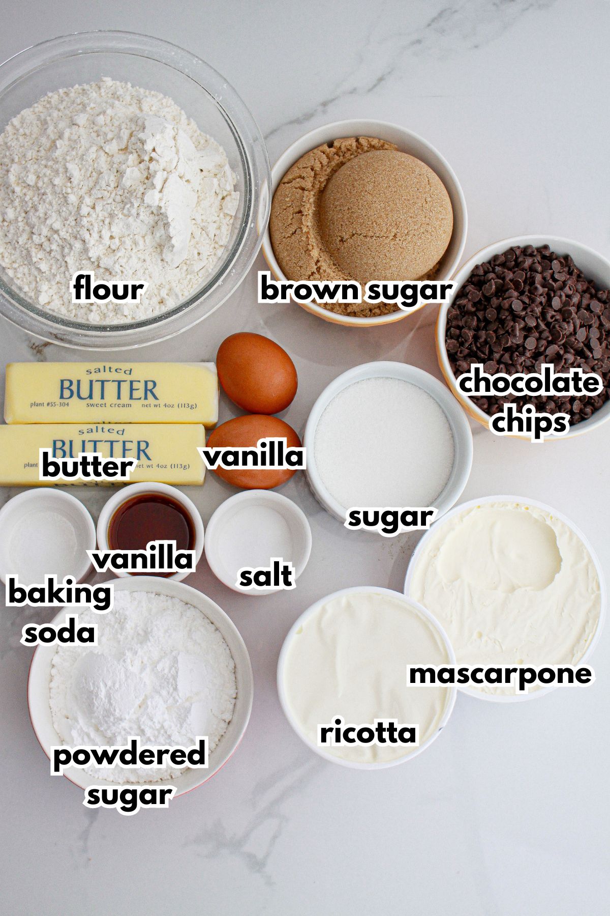 bowls of flour, brown sugar, chocolate chips, butter, vanilla, sugar, baking soda, vanilla, salt, powdered sugar, ricottam and mascarpone cheese.