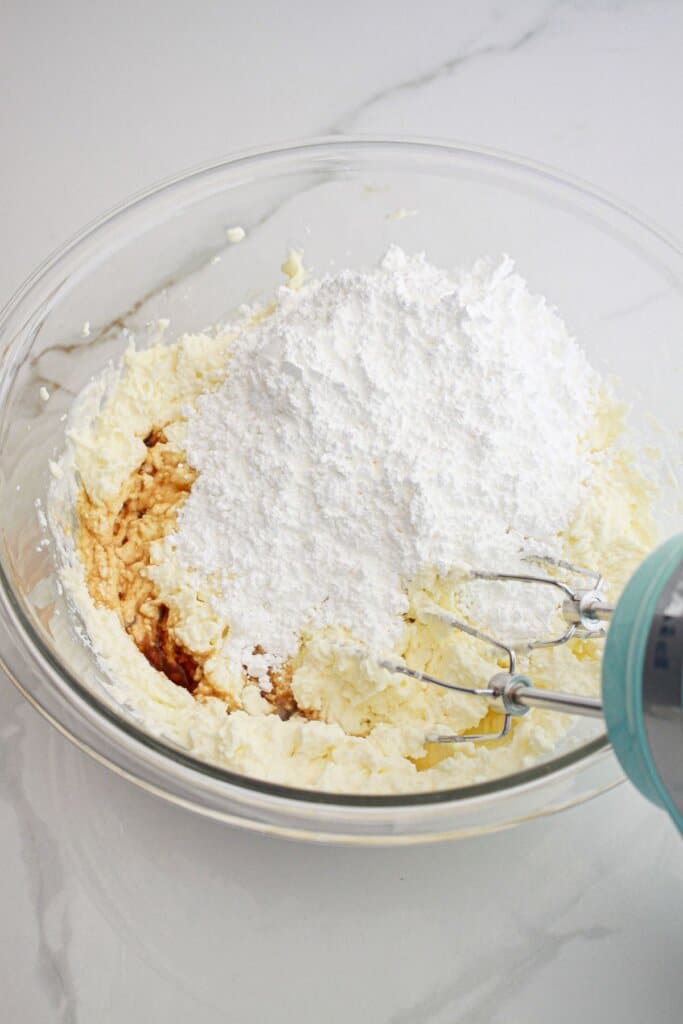 powdered sugar being added to marscapone and ricotta cheese.