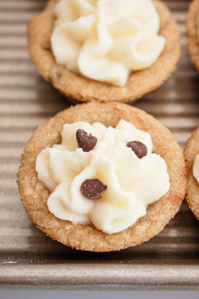 chocolate chips being sprinkles on top of cannoli cookie cups.