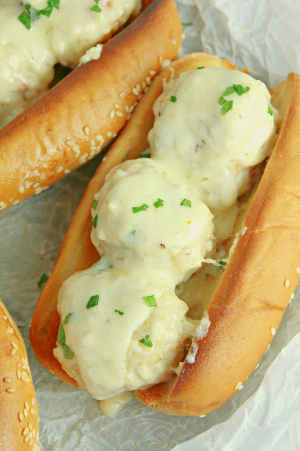 three chicken meatball subs on a parchment lined basket.