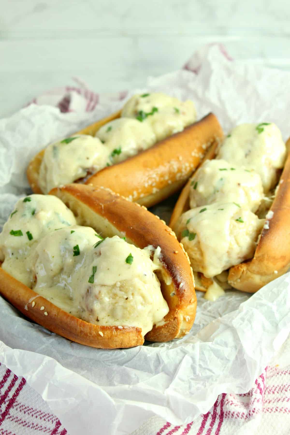 three chicken meatball subs on a parchment lined basket.