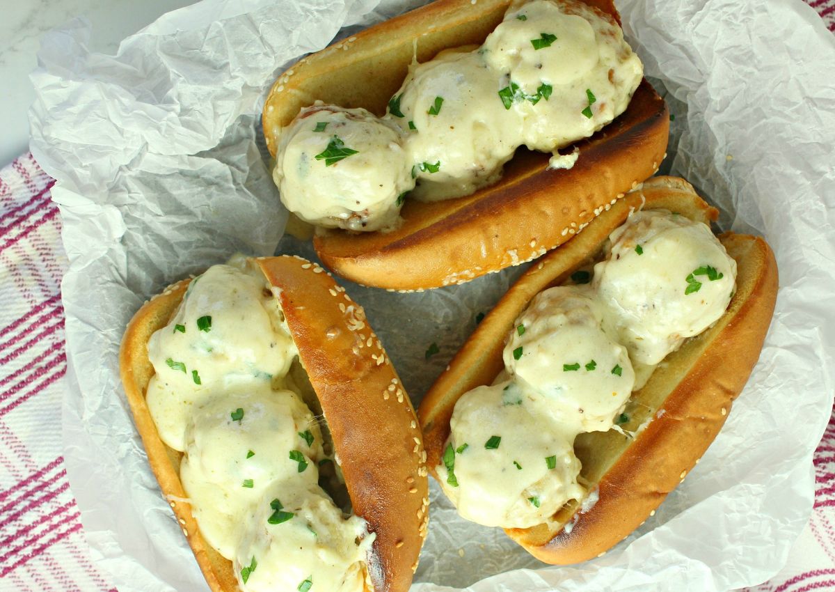 three chicken meatball subs on a parchment lined basket.
