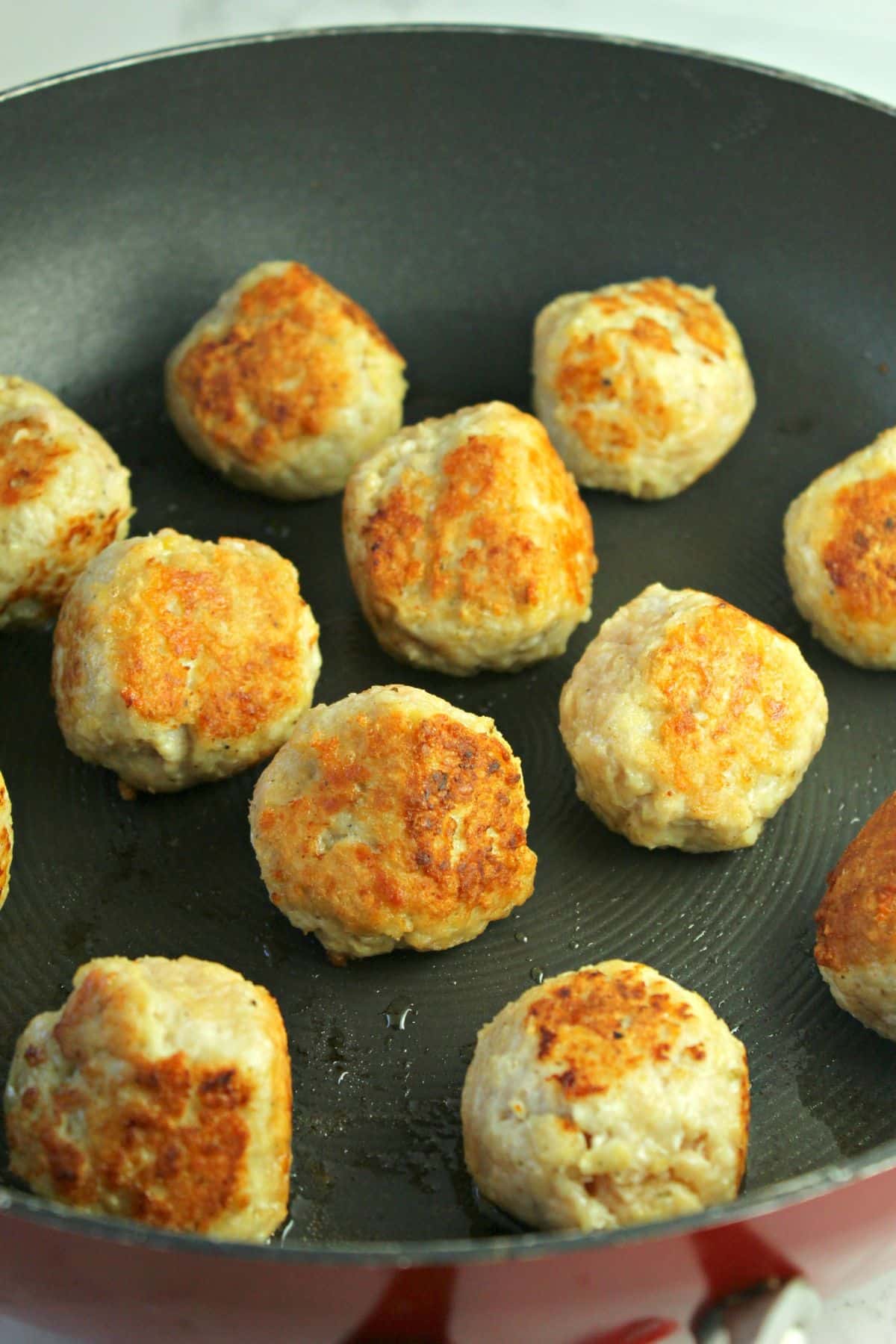 meatballs being seared in a skillet.