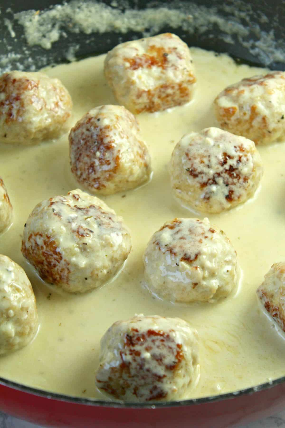 meatballs and cream sauce being cooked in a large skillet.