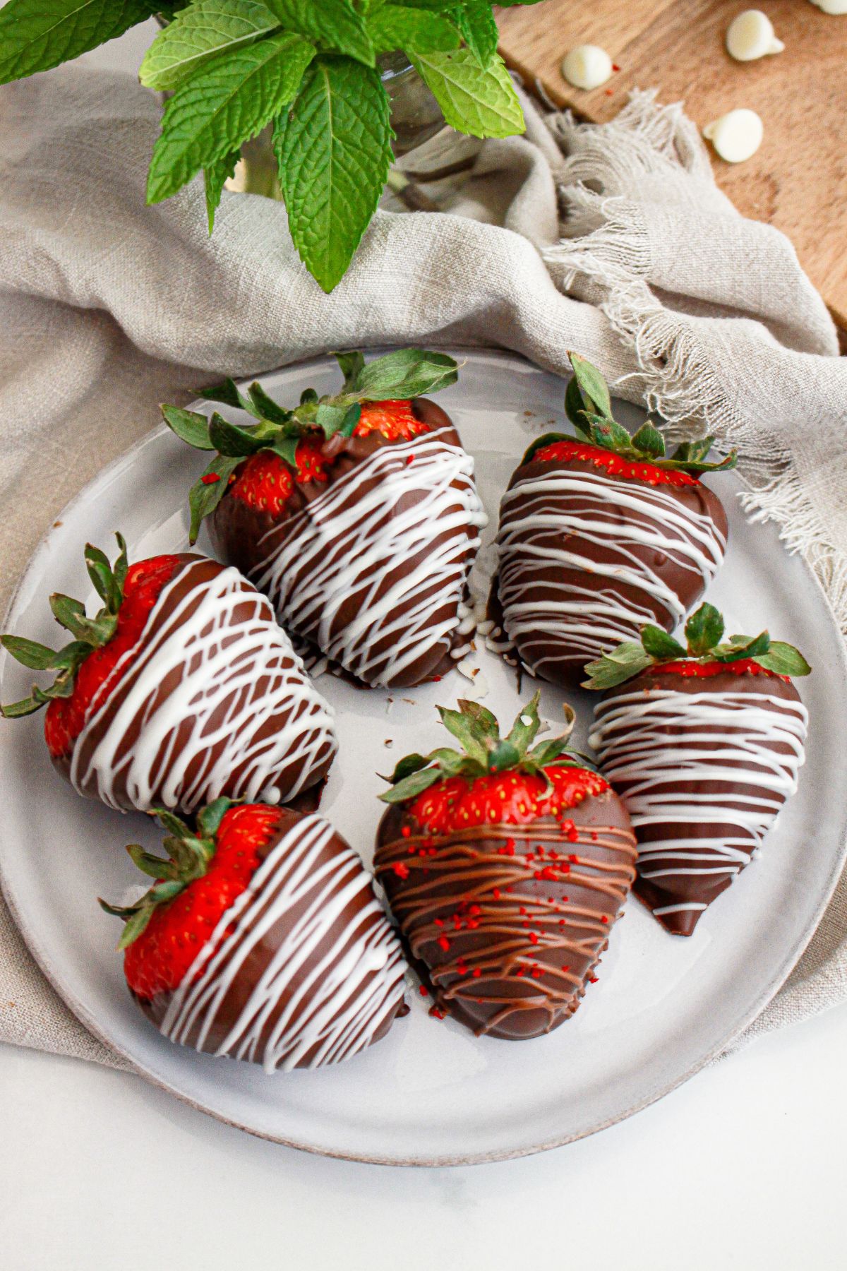Six chocolate dipped strawberries on a plate.