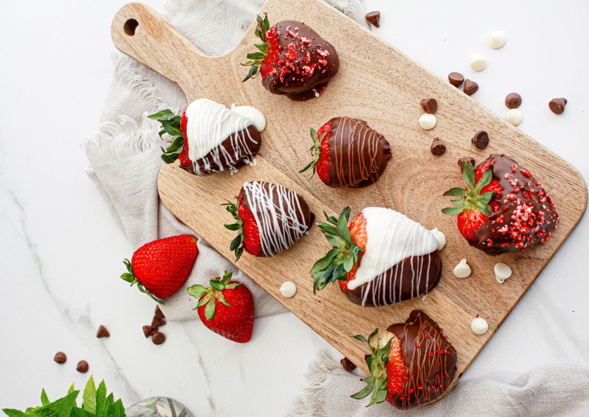 Chocolate dipped strawberries on a wooden cutting board.