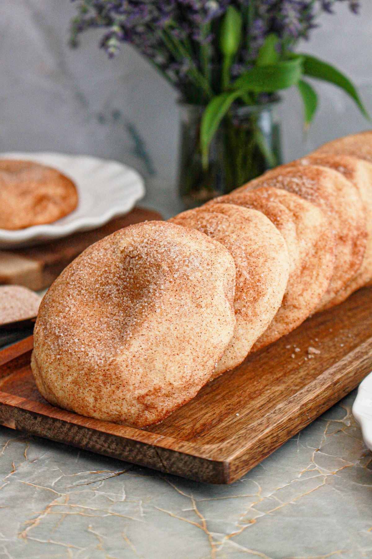 Five churro cheesecake cookies on a wooden cutting board.