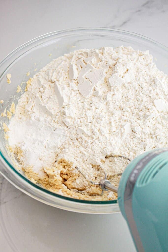 Dry ingredients being mixed into dough with a hand mixer.