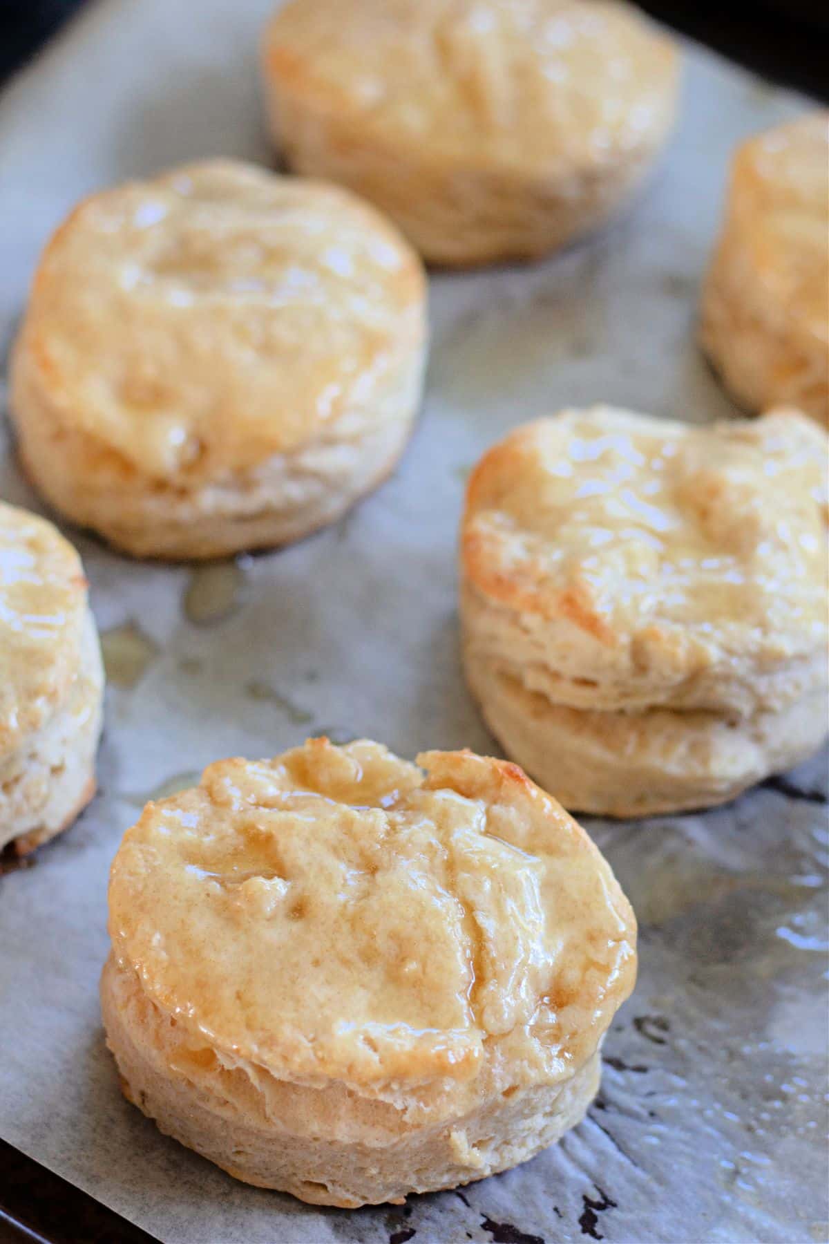 honey butter brushed on top of biscuits on a baking sheet.