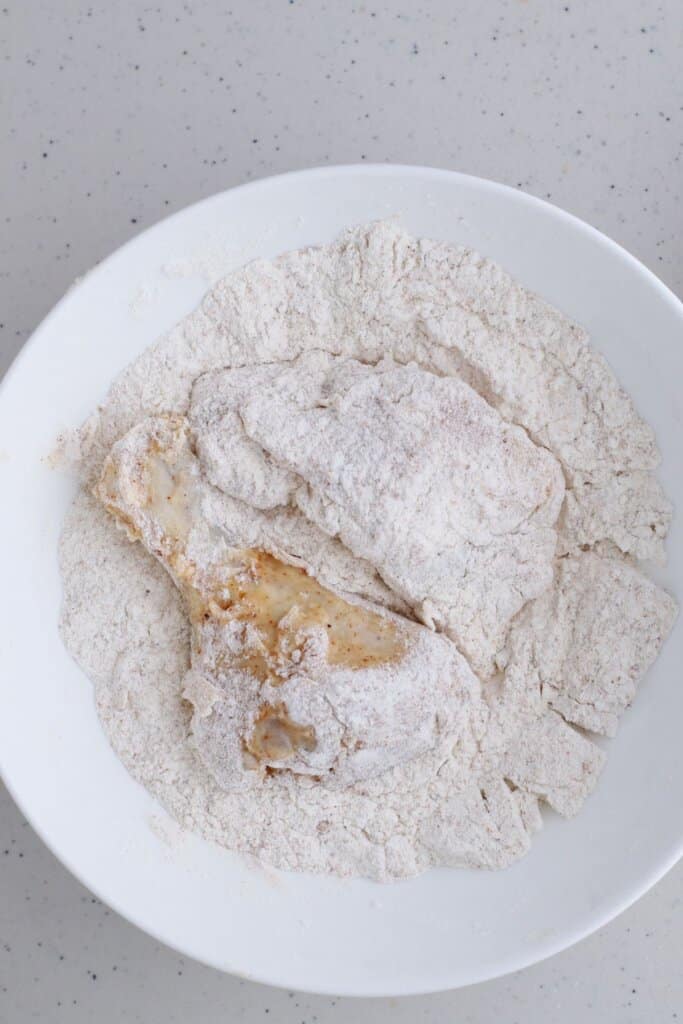 meat pieces being dredged in flour on a plate.