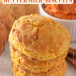Three pumpkin buttermilk biscuits stacked on top of each other on a counter.
