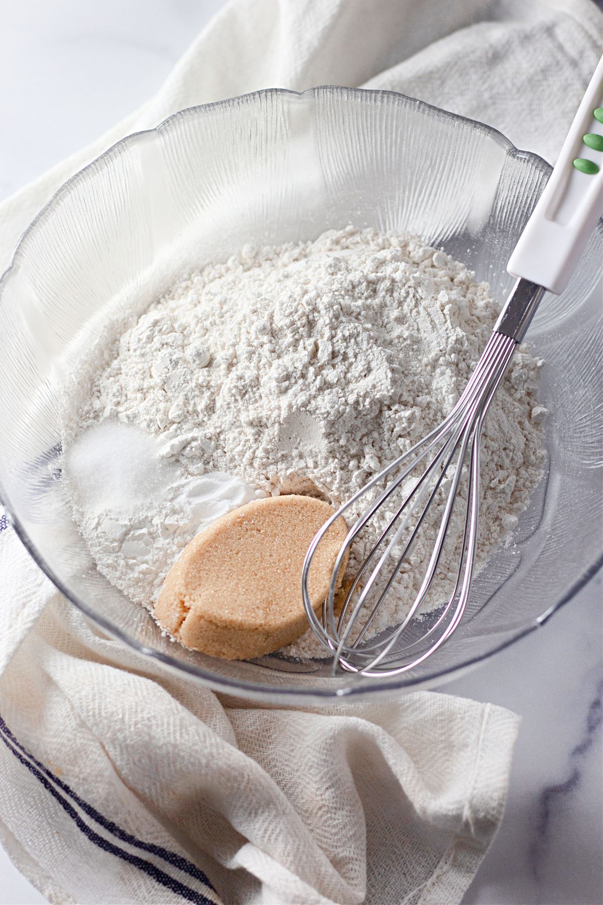 Flour, baking soda, baking powder, salt, and brown sugar being mixed together in large bowl.