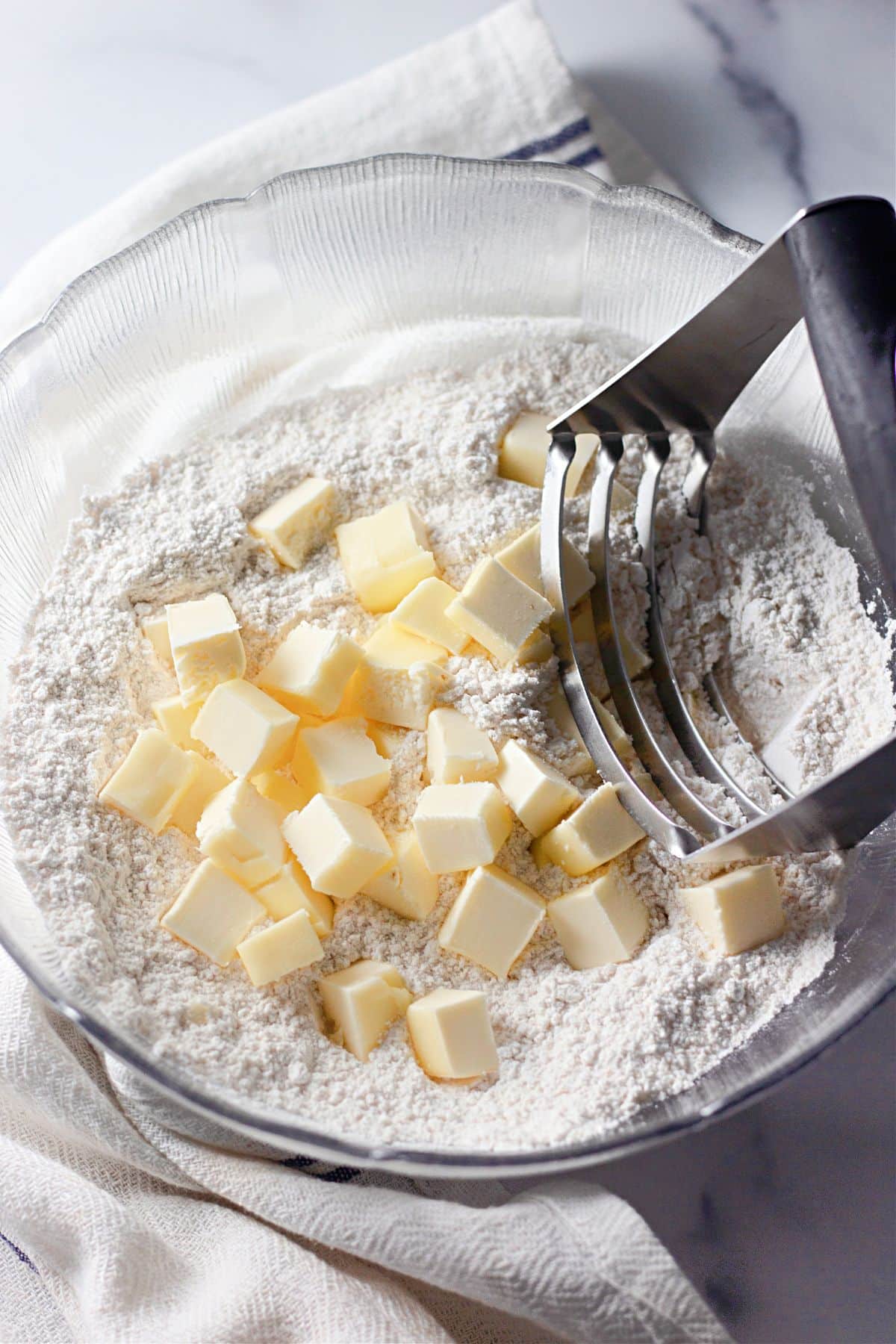 Cold butter being cut into flour with a pastry blender.