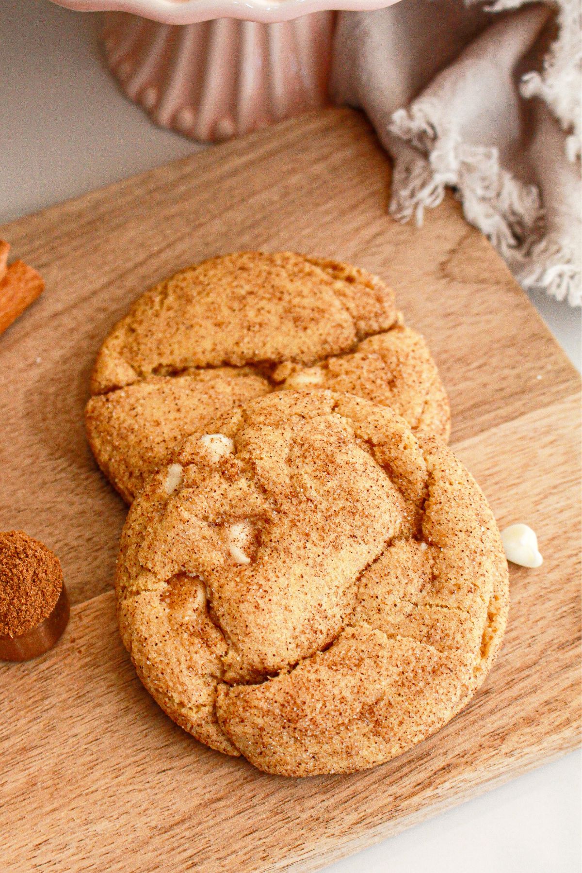 Two pumpkin snickerdoodles on a wooden cutting board.