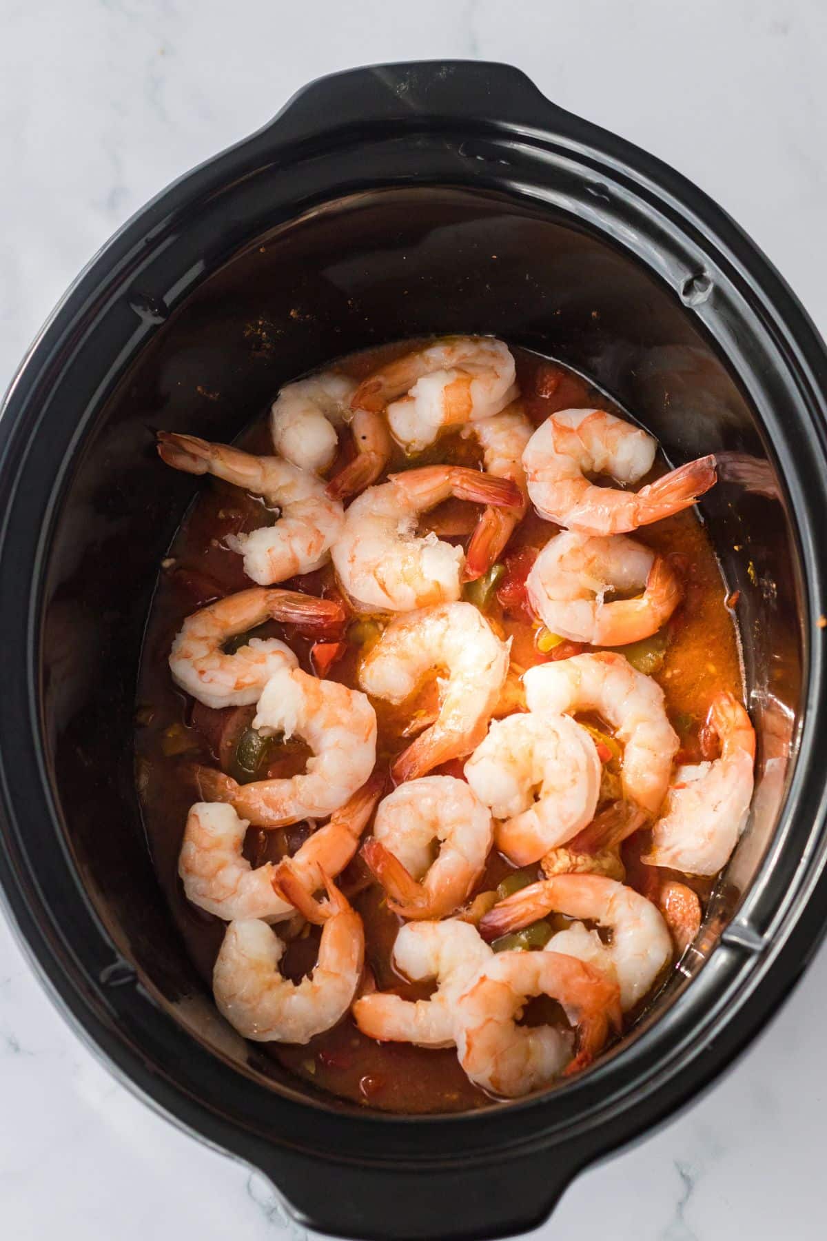 Shrimp being added to the crockpot.