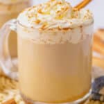 Slow cooker pumpkin spice latte in a glass mug topped with a cinnamon stick.