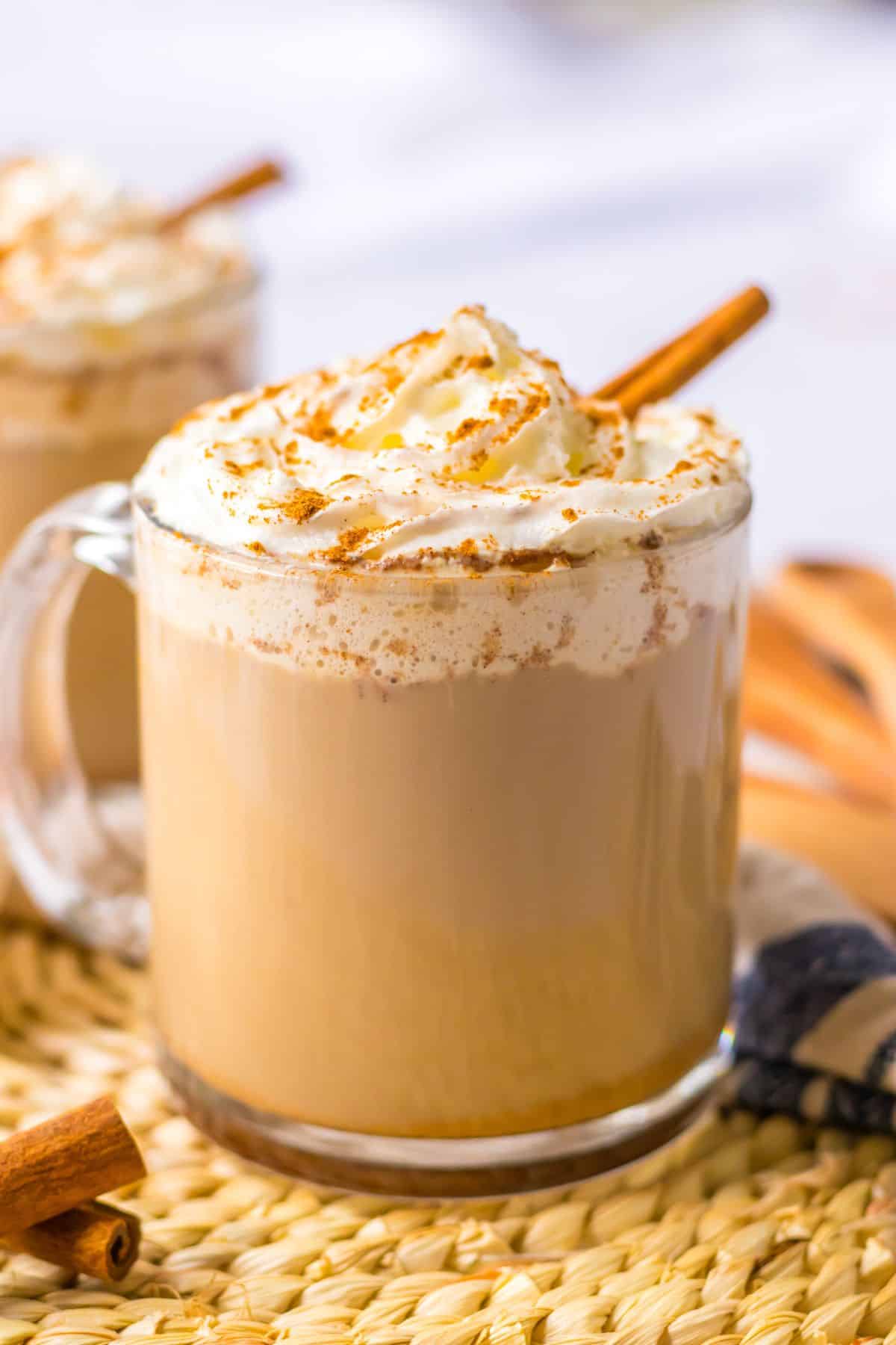 Slow cooker pumpkin spice latte in a glass mug topped with a cinnamon stick.