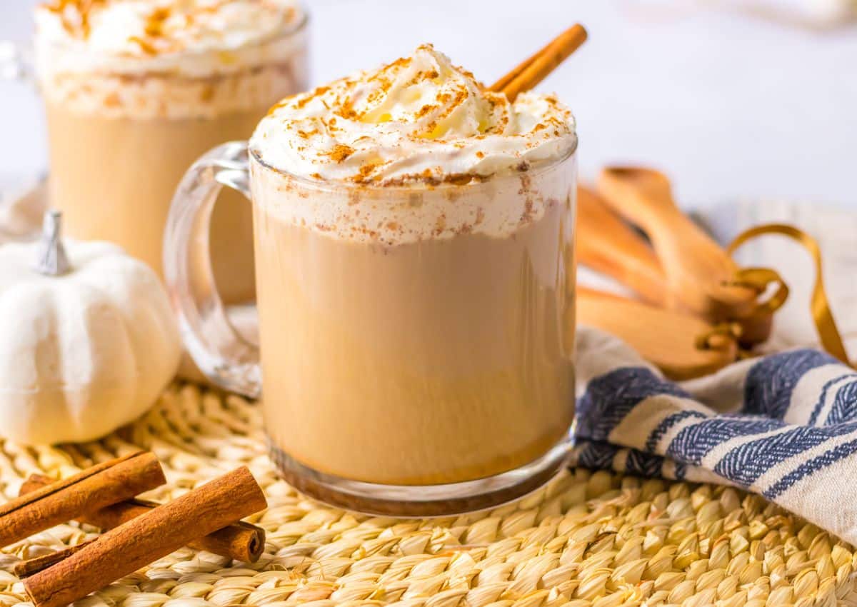 Slow cooker pumpkin spice latte in a glass mug topped with a cinnamon stick.