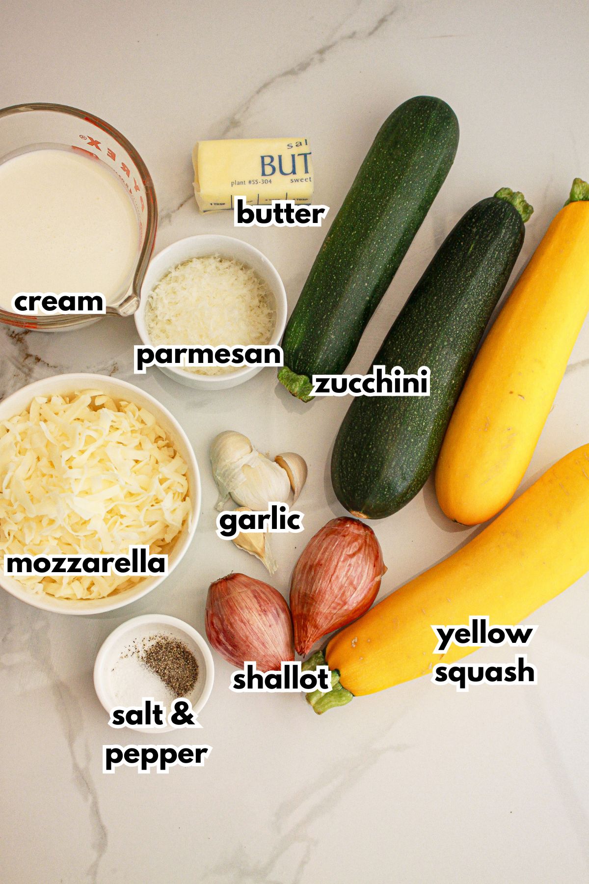 cream, mozzarella, salt, pepper, garlic, shallots, butter, zucchini, and yellow squash on a counter.